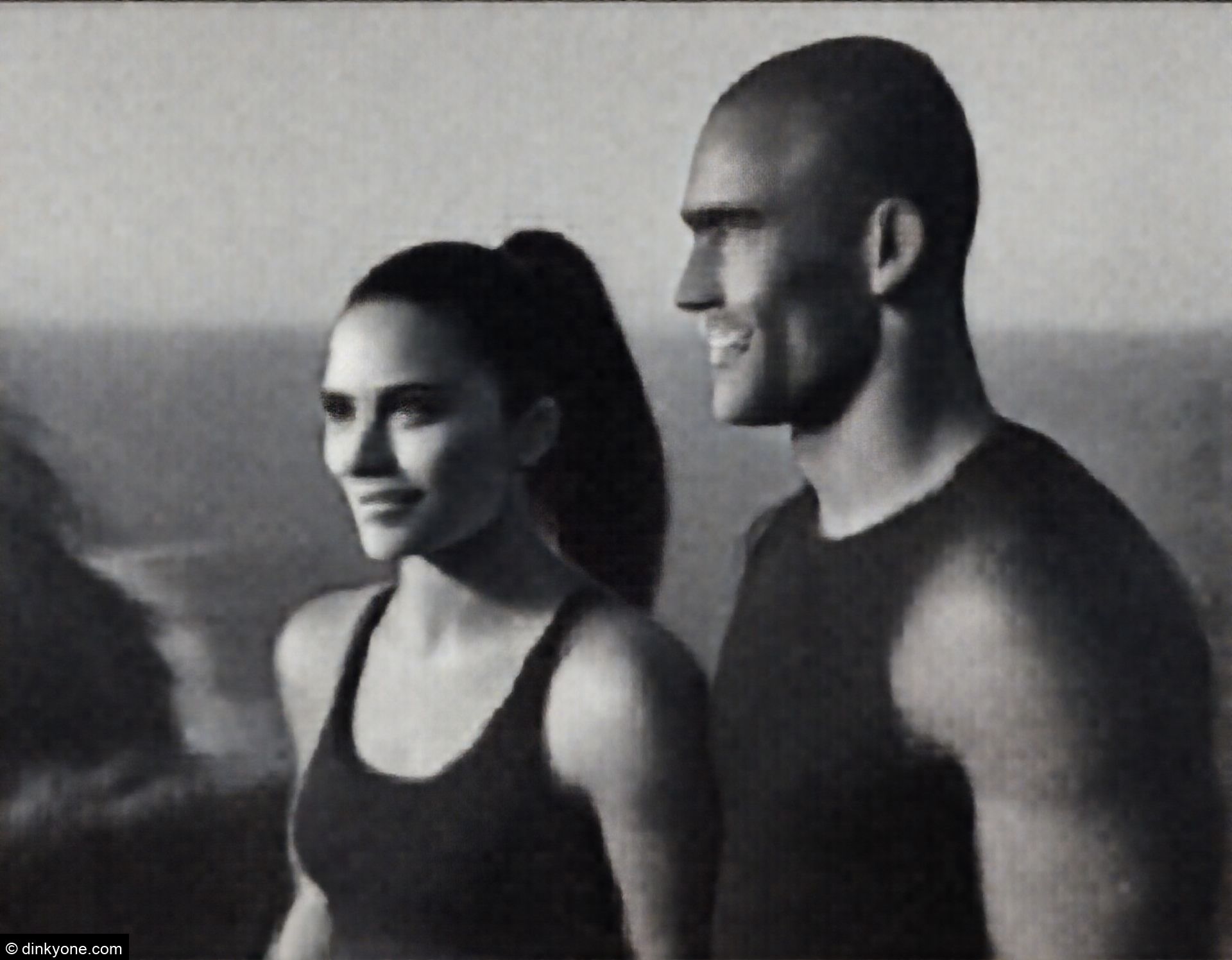 An athletic couple at a clifftop viewpoint overlooking the coastline.