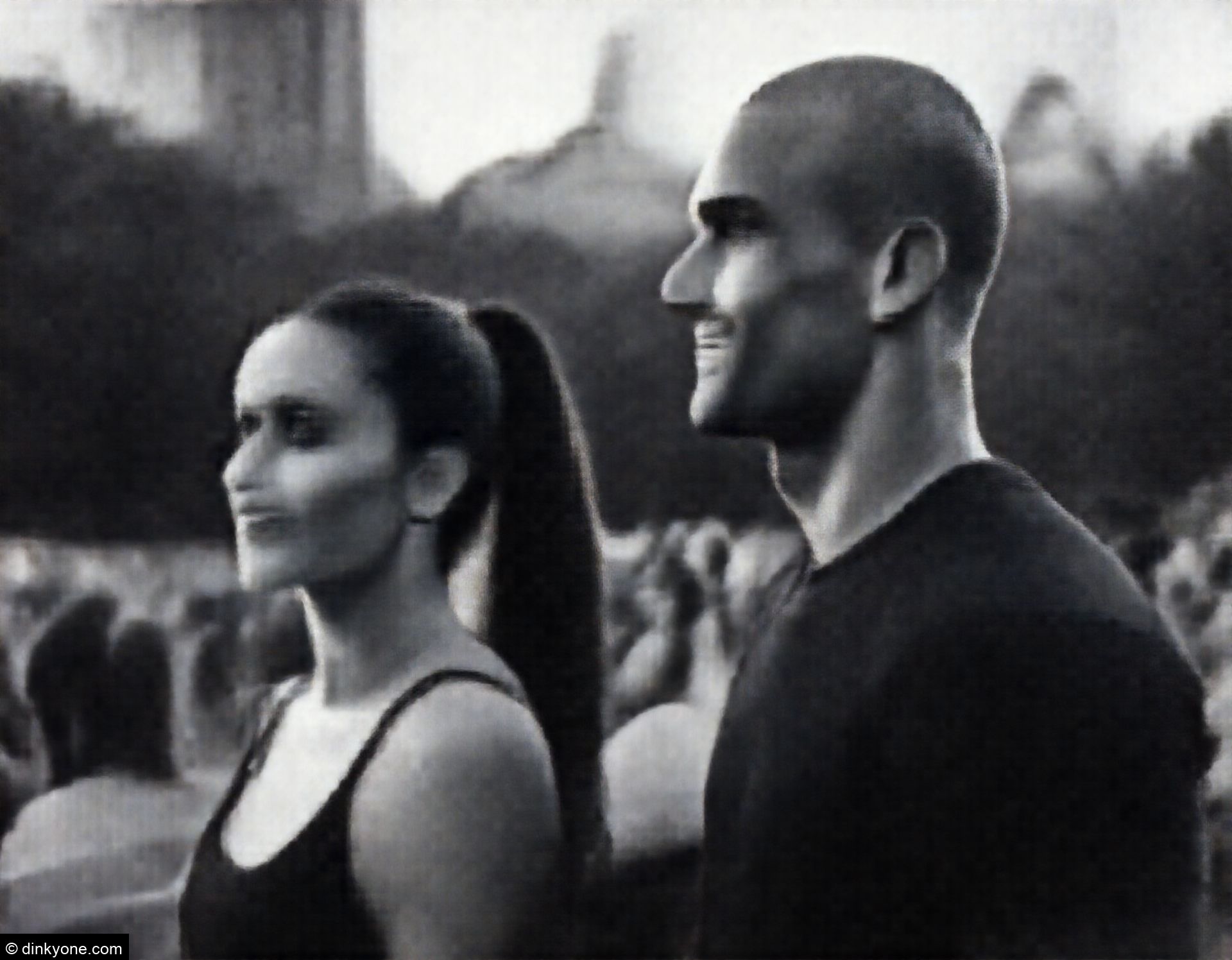 An athletic couple at an open air concert in a city park.