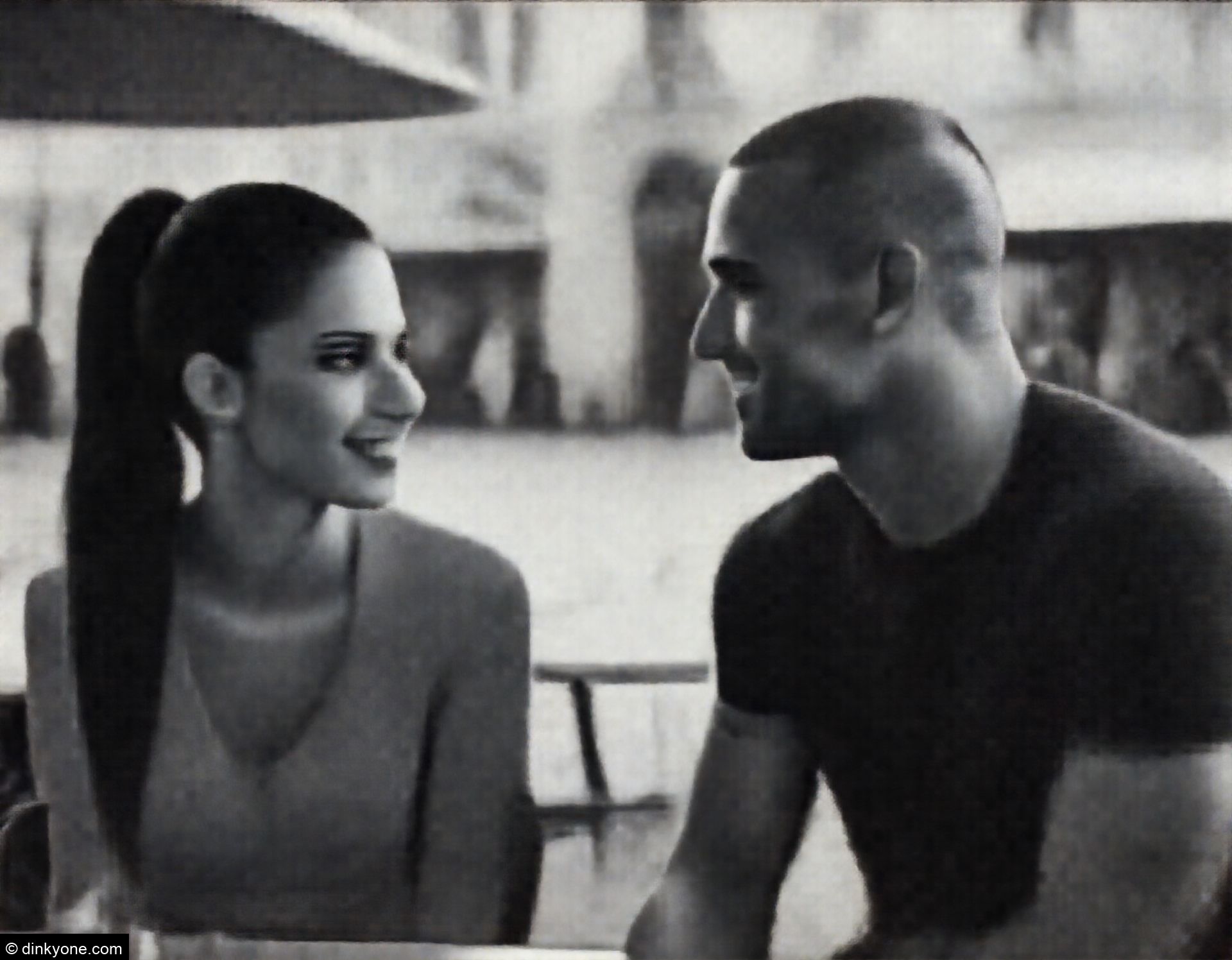 An athletic couple at an outdoor cafe in a pedestrian square.