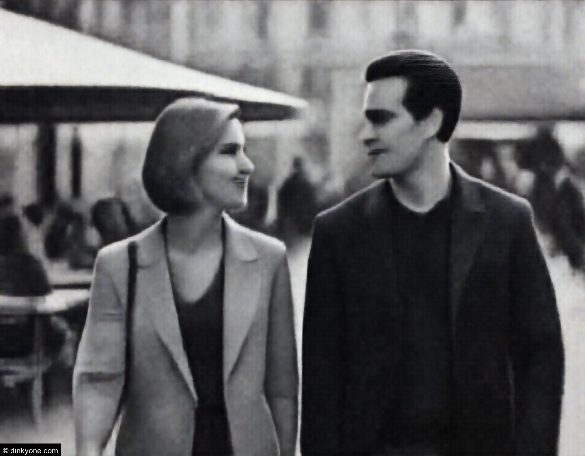 A couple in a busy city square with outdoor seating.