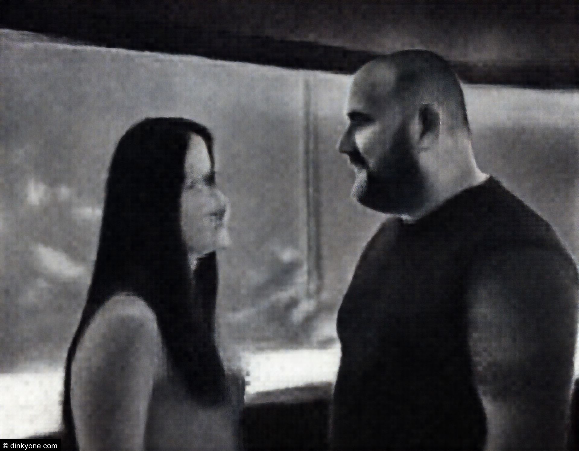 A couple inside an aquarium with large viewing tanks containing fish.