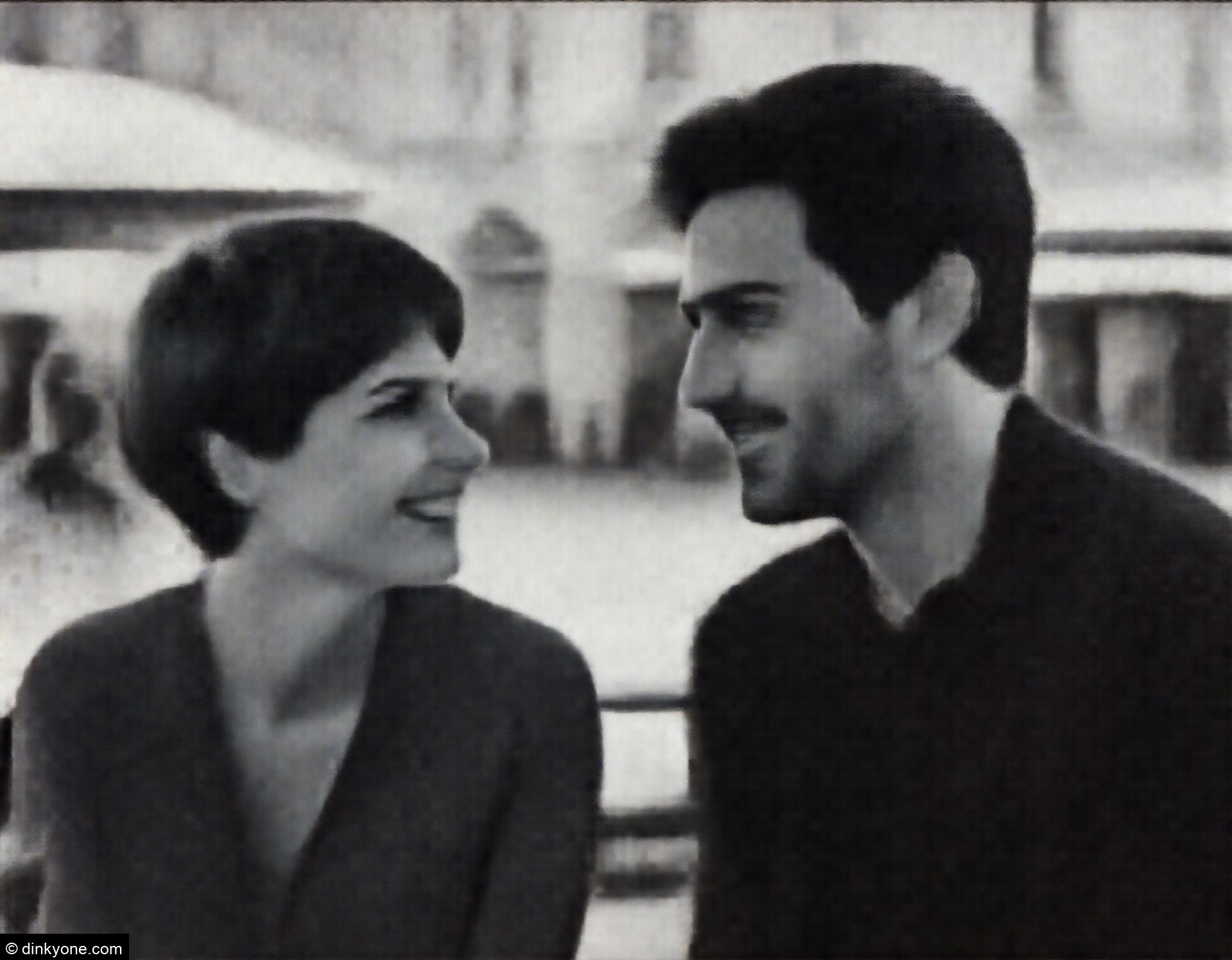 A couple at an outdoor cafe in a pedestrian square.