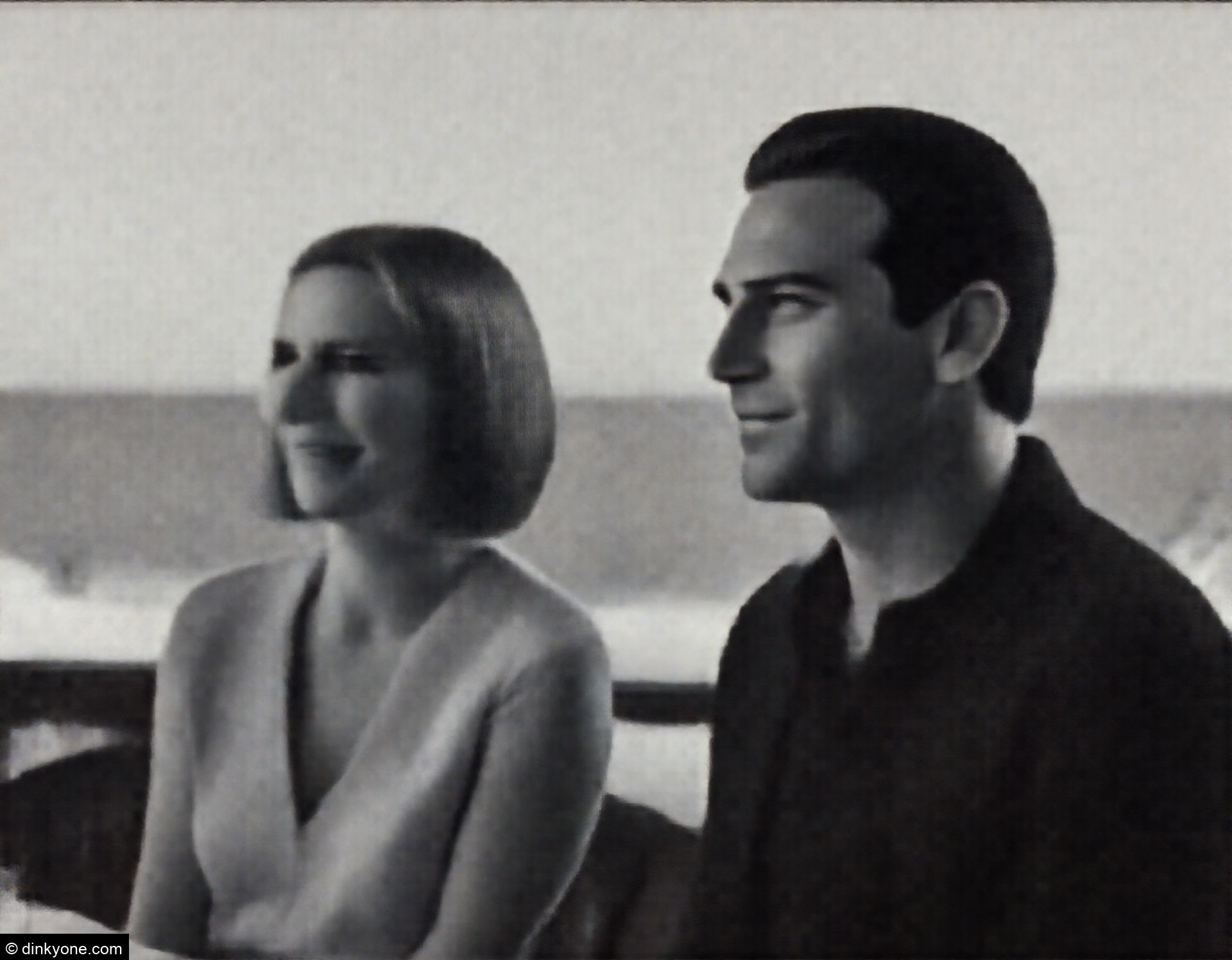 A couple at an outdoor restaurant terrace overlooking the ocean.