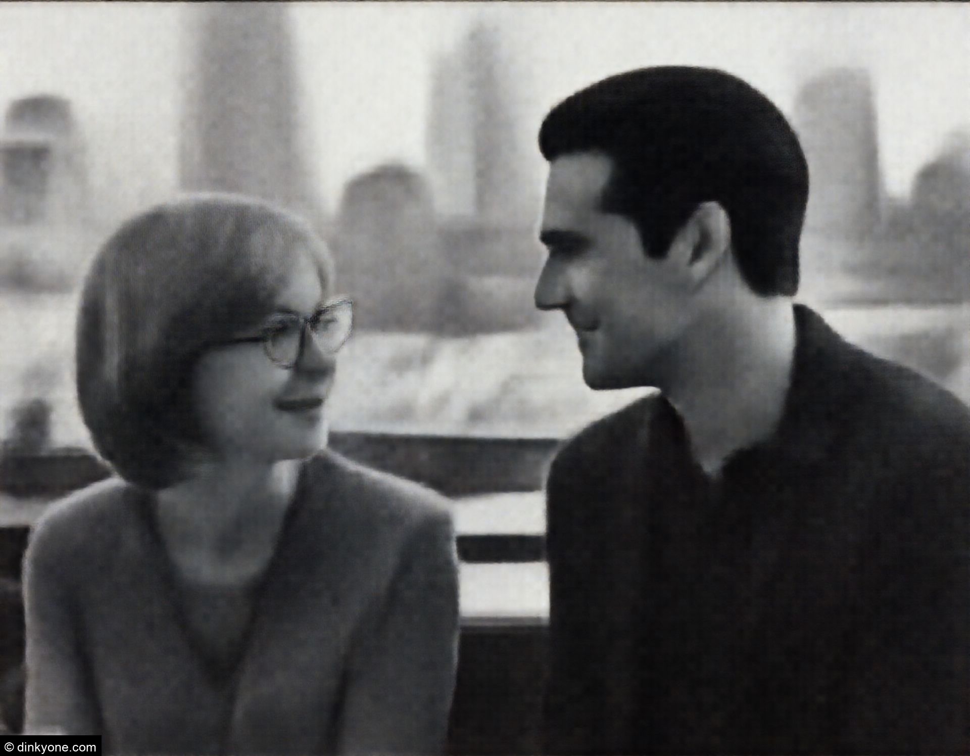 A couple at a rooftop cafe overlooking the city skyline.