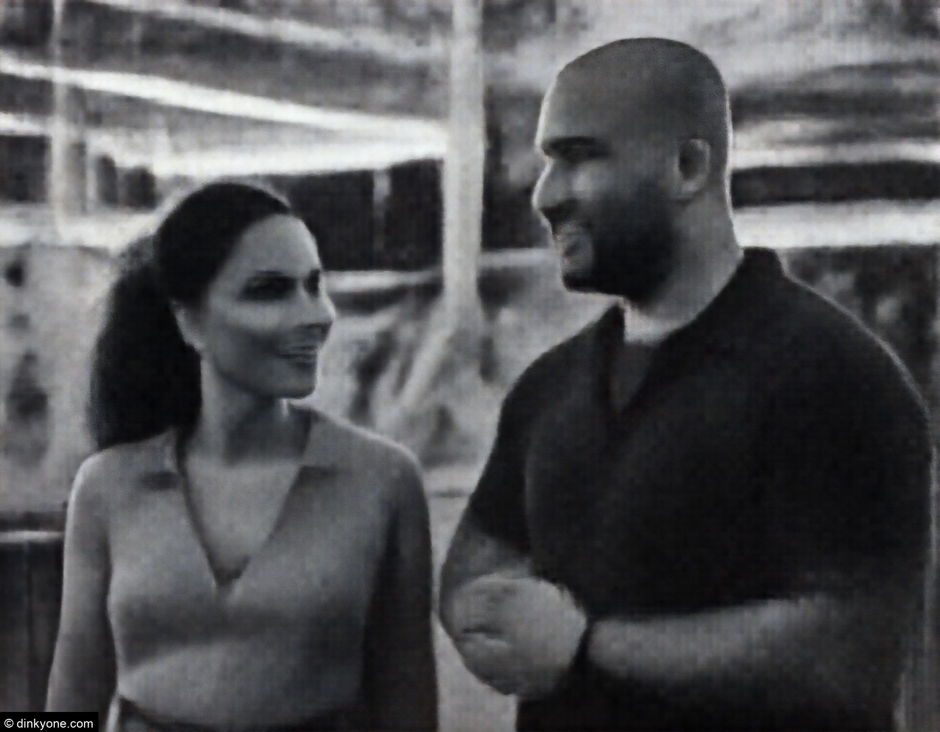 A strong-looking couple at an amusement park with lights.