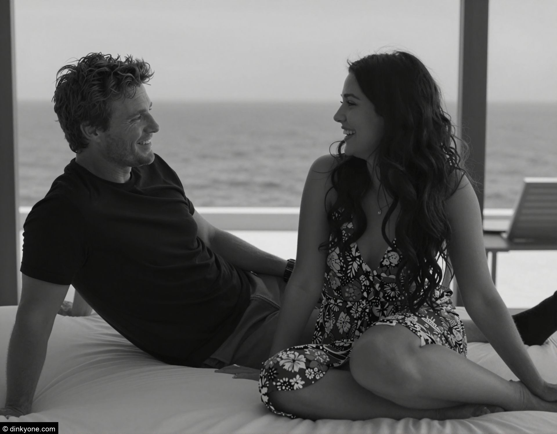 A young couple in a high end resort bedroom overlooking the ocean.