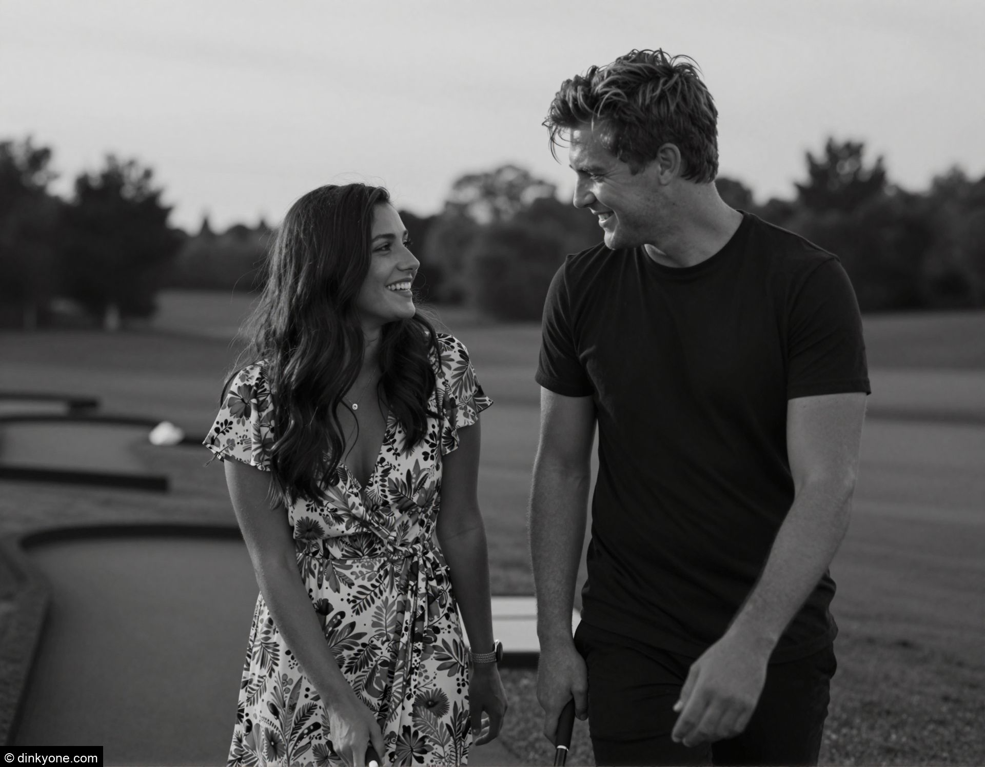 A young couple at a mini golf course on a summer evening.